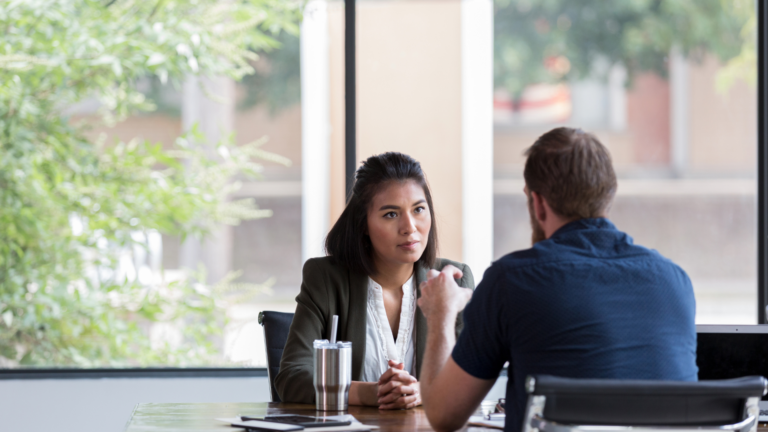 female manager actively listening to male employee at a table